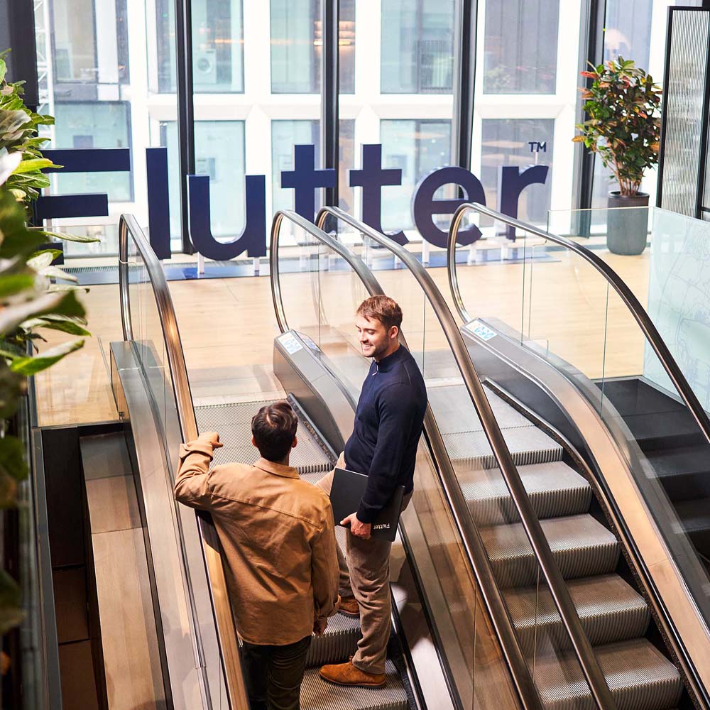Colleagues using the escalator in the Flutter offices